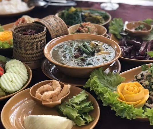 Laos Mutfağı Laos, Güneydoğu Asya’nın iç kesimlerinde yer alan ve Mekong Nehri boyunca uzanan bir ülkedir. Bu konum, Laos mutfağının hem Tayland hem de Vietnam mutfaklarından etkilenmesini sağlamıştır. Pirinç, balık ve taze sebzeler, Laos mutfağının temel besin kaynaklarını oluşturur. Baharatlar ve taze otlar, yemeklerde hem aroma hem de karakter kazandırır. Laos mutfağı, lezzet çeşitliliği ve kültürel derinliği ile dikkat çeker. Konulu bir haber görseli.