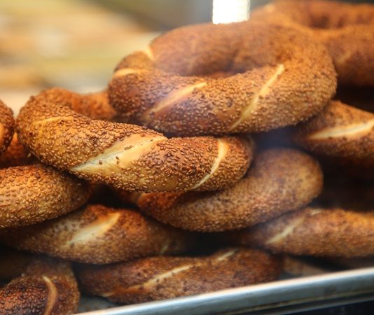Simit, Osmanlı döneminden günümüze kadar gelen köklü bir geçmişe sahiptir. İlk olarak saray mutfaklarında farklı un karışımlarıyla yapılan bu lezzet, zamanla halk arasında yaygınlaşarak günlük yaşamın bir parçası haline gelmiştir. Özellikle 16. yüzyıldan itibaren İstanbul’da simit fırınlarının açılmasıyla birlikte, bu eşsiz yiyecek şehir kültürünün önemli bir unsuru olmuştur.