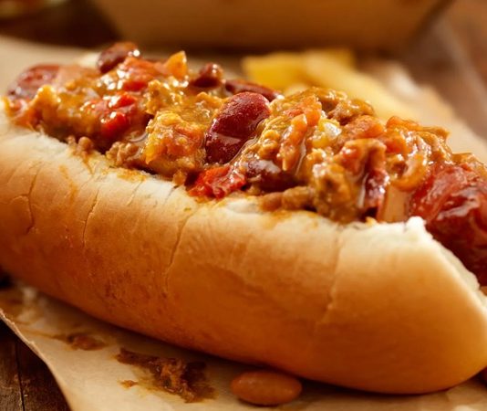 Amerika mutfağının en sevilen sokak lezzetlerinden biri olan chili dog, klasik hot dog’un baharatlı bir versiyonudur. Kökeni 20. yüzyılın başlarına uzanan bu yiyecek, özellikle Teksas ve Kaliforniya sokaklarında popüler hale gelmiştir. Klasik sosis ve ekmek kombinasyonunun üzerine eklenen acılı chili sos, chili dog’un karakteristik özelliğini oluşturur. Konulu bir haber görseli.