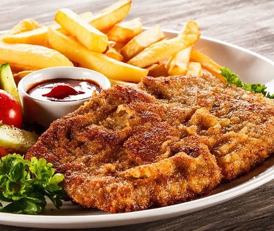 Avrupa mutfaklarının en sevilen yemeklerinden biri olan dana şinitzel, aslen Avusturya’nın başkenti Viyana’da doğmuş ve kısa sürede dünyaya yayılmıştır. Viyana usulü şinitzelin temel özelliği, ince dövülmüş etin galeta unu ile kaplanıp kızartılmasıdır. Bu yöntem, hem etin yumuşak kalmasını sağlar hem de dışının çıtır çıtır olmasına yardımcı olur. Konulu bir haber görseli.