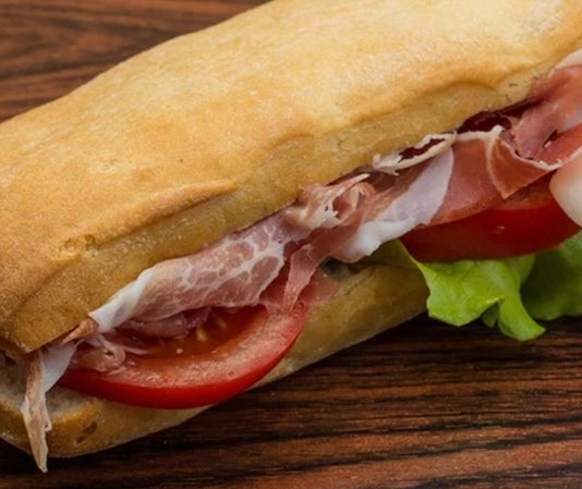 Jambonlu sandviç, dünya mutfaklarında uzun yıllardır popüler olan klasik bir öğün seçeneğidir. İngiltere’de Sandviç Kontu John Montagu’nun öğle yemeklerinde pratik bir seçenek arayışıyla ortaya çıktığı rivayet edilir. O dönemde ekmek arasına yerleştirilen jambon, hem kolay taşınabilir hem de hızlı bir öğün olma özelliğiyle dikkat çekmiştir. Konulu bir haber görseli.