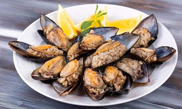 Midye Dolma Sokakların Vazgeçilmez Lezzeti Türk mutfağının en bilinen sokak lezzetlerinden biri olan midye dolma, kökeni Osmanlı dönemine kadar uzanan köklü bir geçmişe sahiptir. Saray mutfağında farklı baharatlarla hazırlanan pirinçli yemeklerin deniz ürünleriyle birleşmesi sonucu ortaya çıktığı düşünülmektedir. Zamanla bu lezzet, sokaklara taşınarak herkesin ulaşabileceği bir hale gelmiştir. Konulu bir haber görseli.