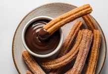 Churros, son yıllarda yalnızca İspanya’nın geleneksel sokak lezzeti olmaktan çıkıp dünya genelinde kafe menülerinin favorisi haline geldi. Özellikle Türkiye’de tatlı kültürünün giderek çeşitlenmesiyle birlikte churros popüler bir alternatif olarak öne çıkıyor. Çıtır yapısı, şeker ve tarçınla kaplanan dış yüzeyi ve sıcak çikolata sosuyla birleştiğinde ortaya çıkan benzersiz tat, birçok insanın yeni gözdesi haline gelmiş durumda. Konulu bir haber görseli.